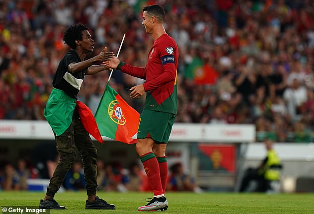 Ronaldo (right) smiled and entertained the pitch invader and performed his famous 'Siu' celebration with the man