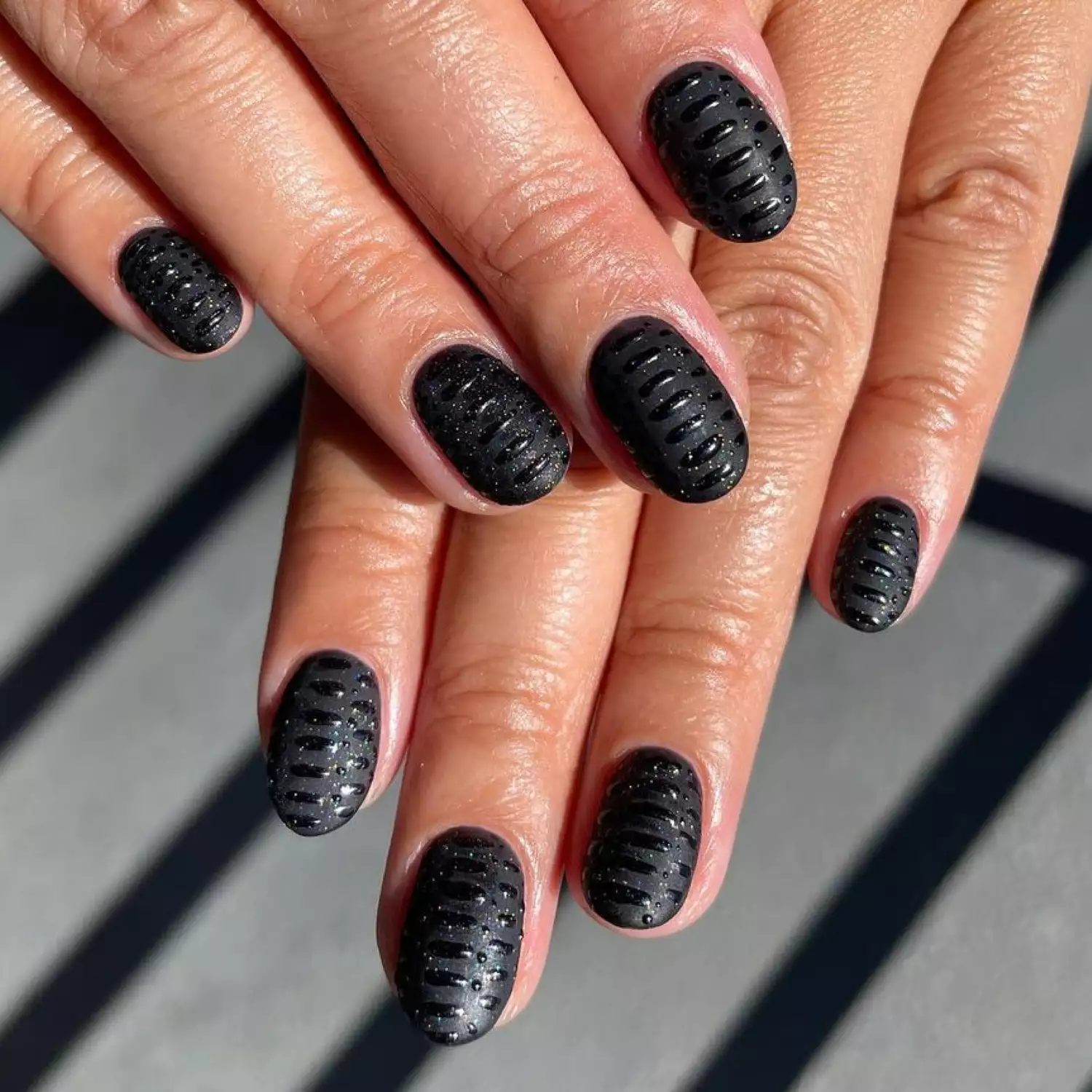 Close-up of matte black manicure with 3D glossy black details