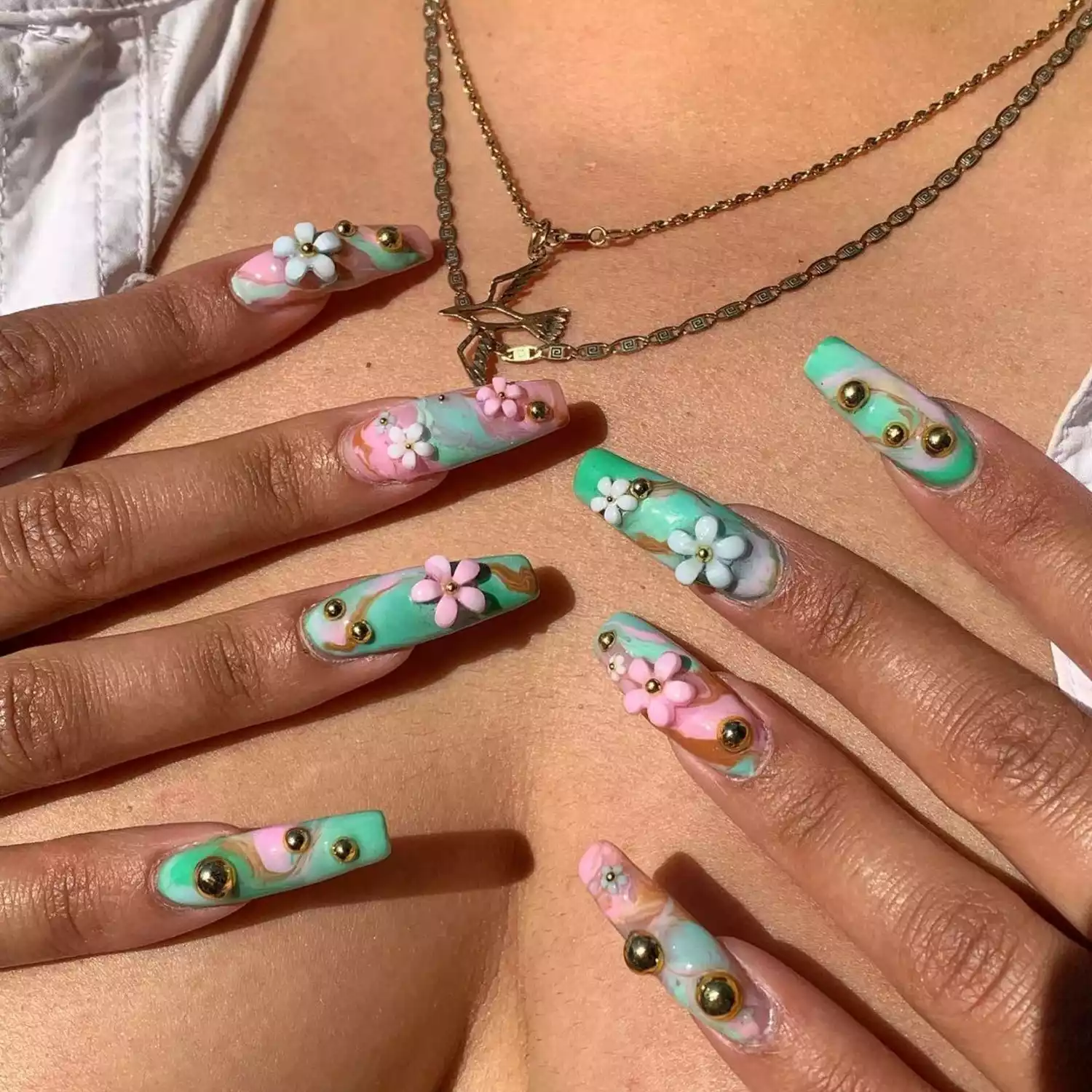 Close-up of manicure with green and pink base and 3D flowers and chrome spheres