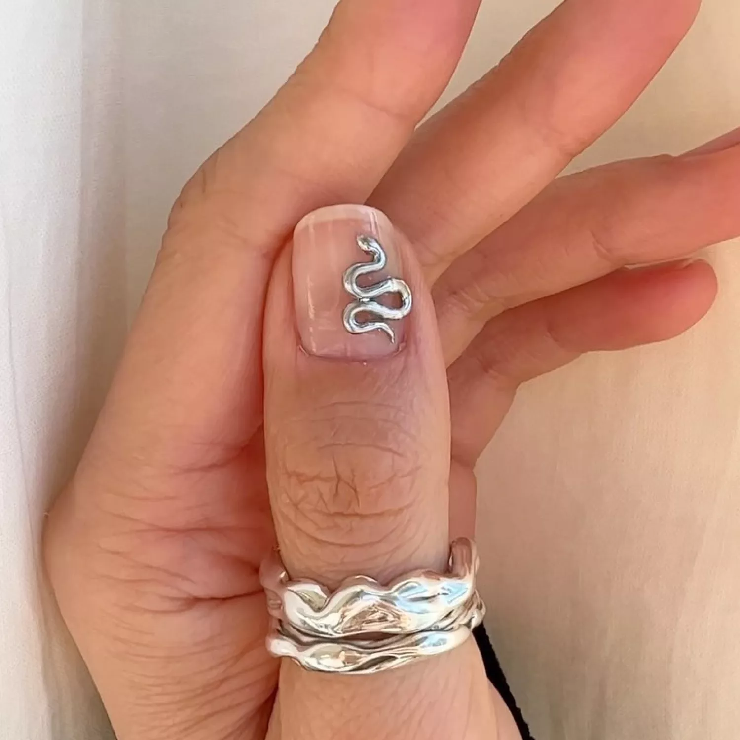 Close-up of manicure with clear base and 3D silver snake design