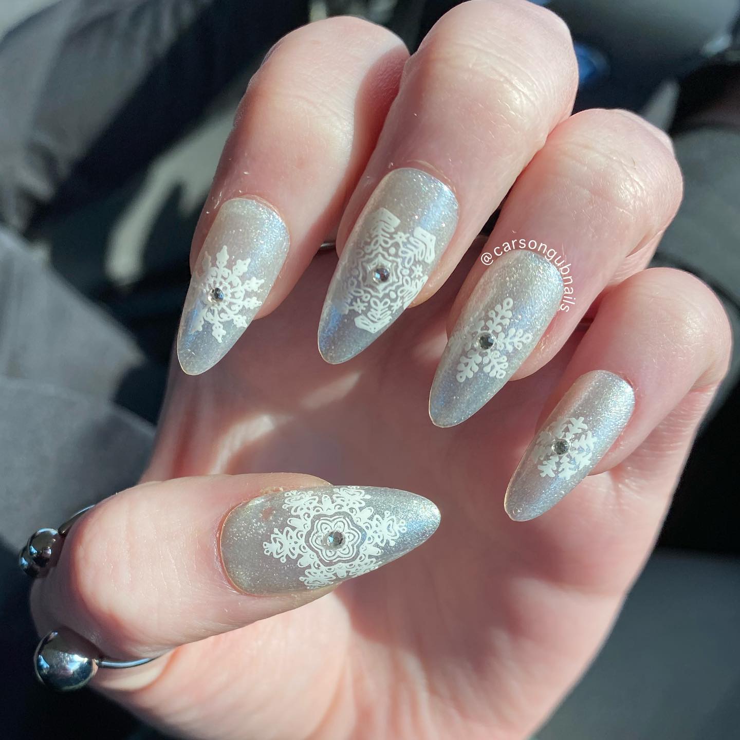 The combination of silver glittered nail polish with white snowflakes is quite matching. Little shiny stones placed in the middle of snowflakes look nice, too.