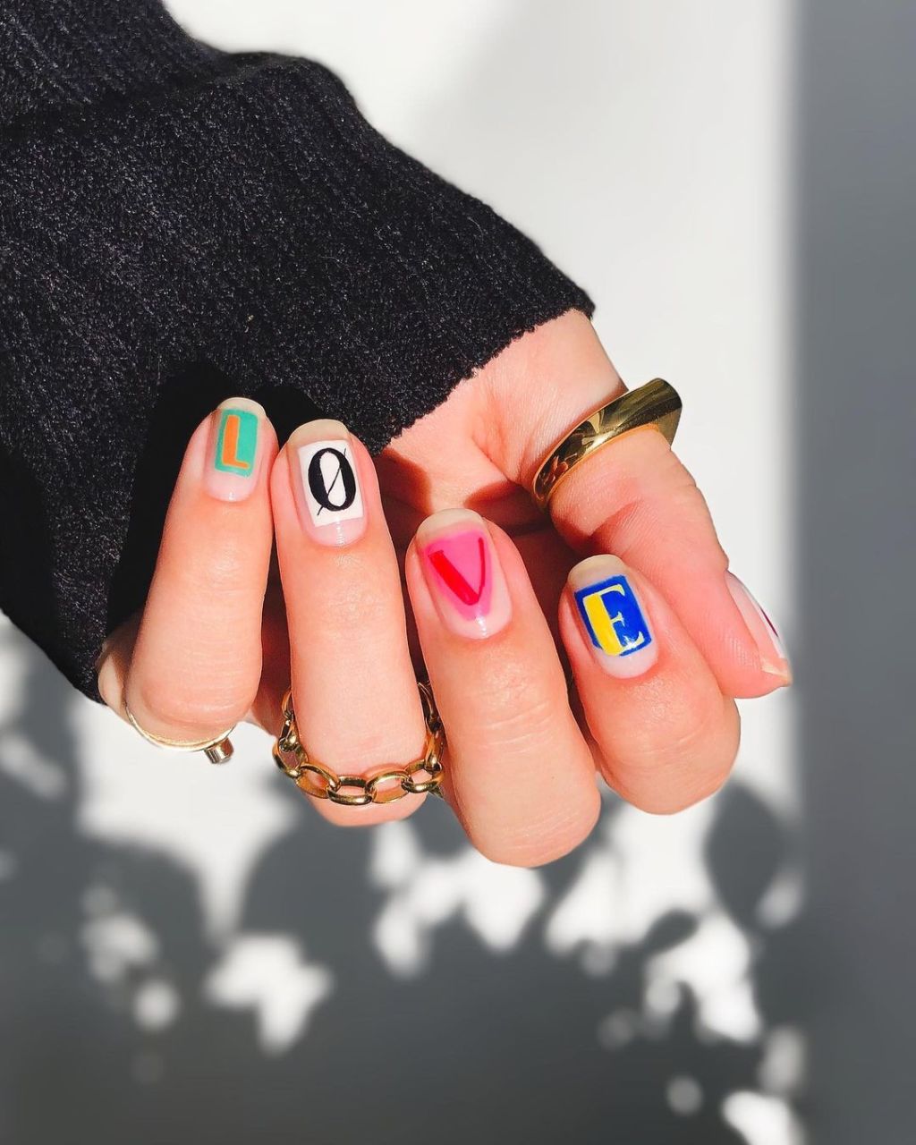 colorful short Valentines Day nails with letter designs that spell out "love"
