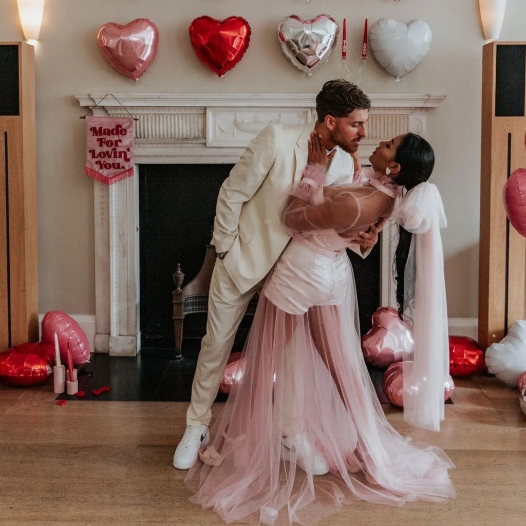 a couple celebrating a romantic night at home with pink and red heart balloons
