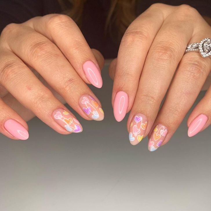 cute light pink manicure with pastel candy heart designs in orange, yellow, purple, and light blue colors