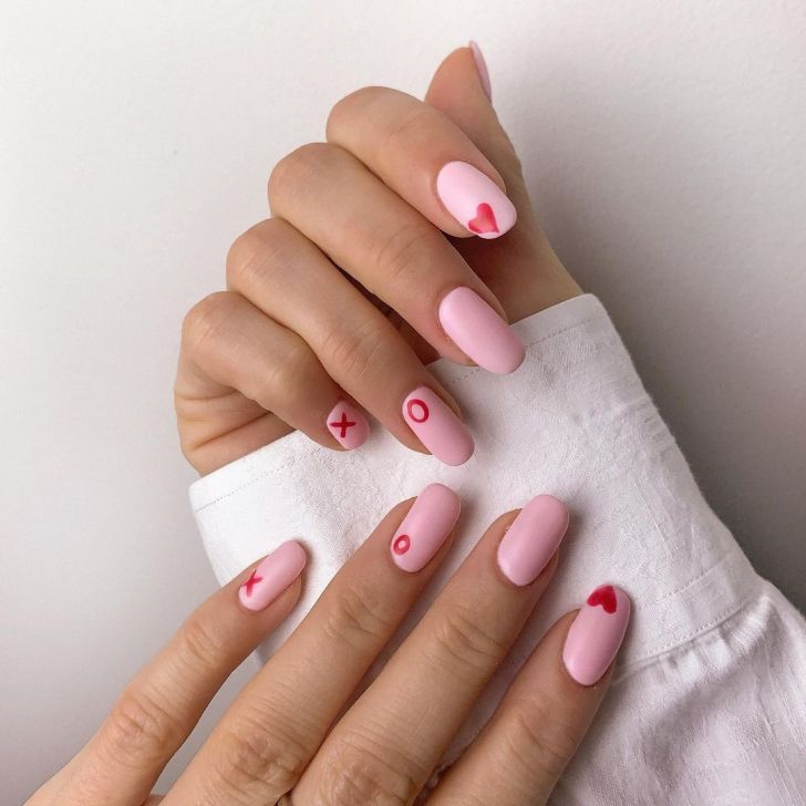 light pink simple Valentines Day nails with cute red nail art with x's o's and hearts