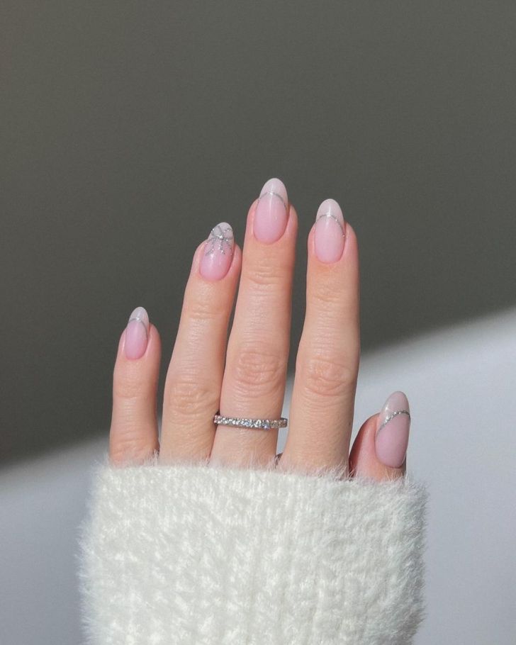 nude Valentines Day nails with simple silver glitter designs and cute bow nail art on the French inspired tips