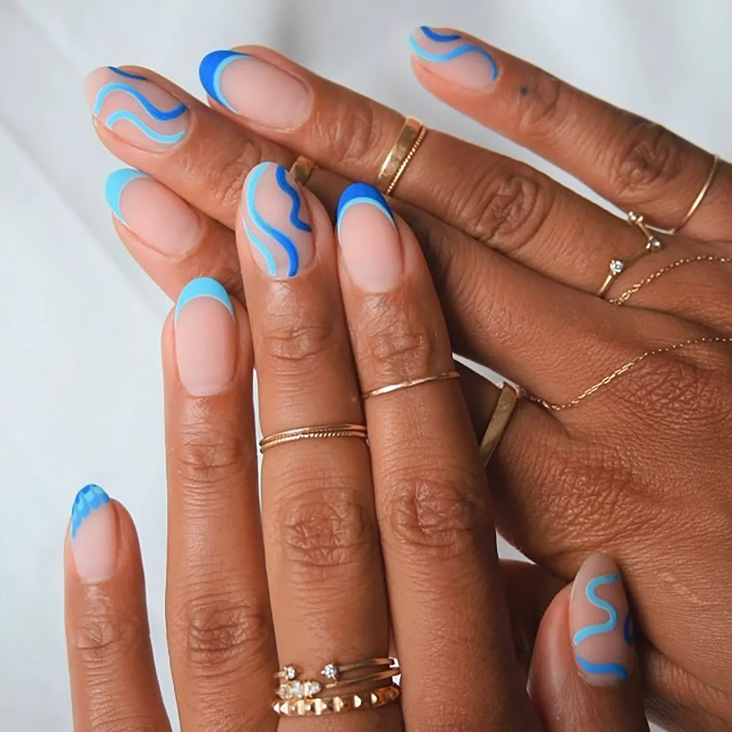 A matte negative space manicure wth blue swirl accent nails