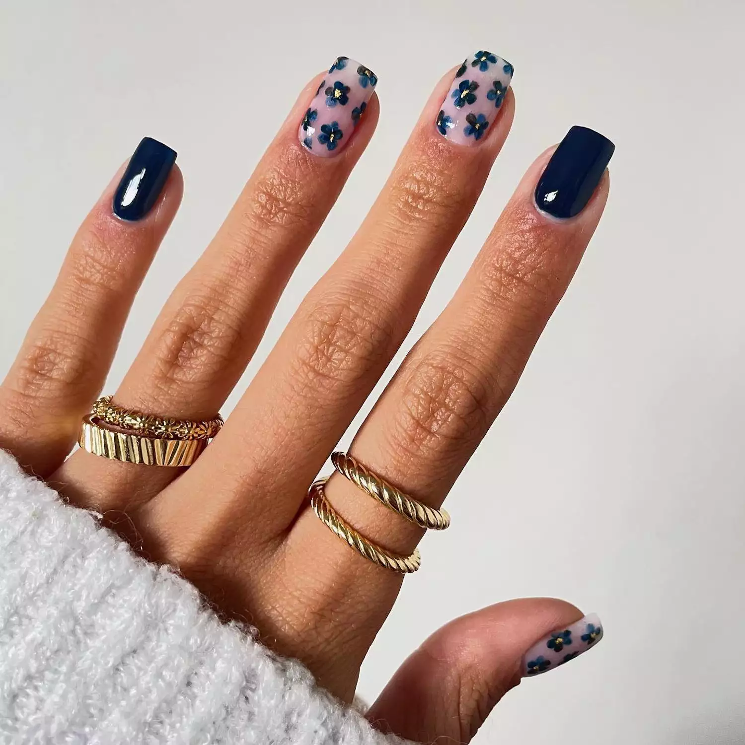 Navy manicure with two solid nails and three retro floral design nails