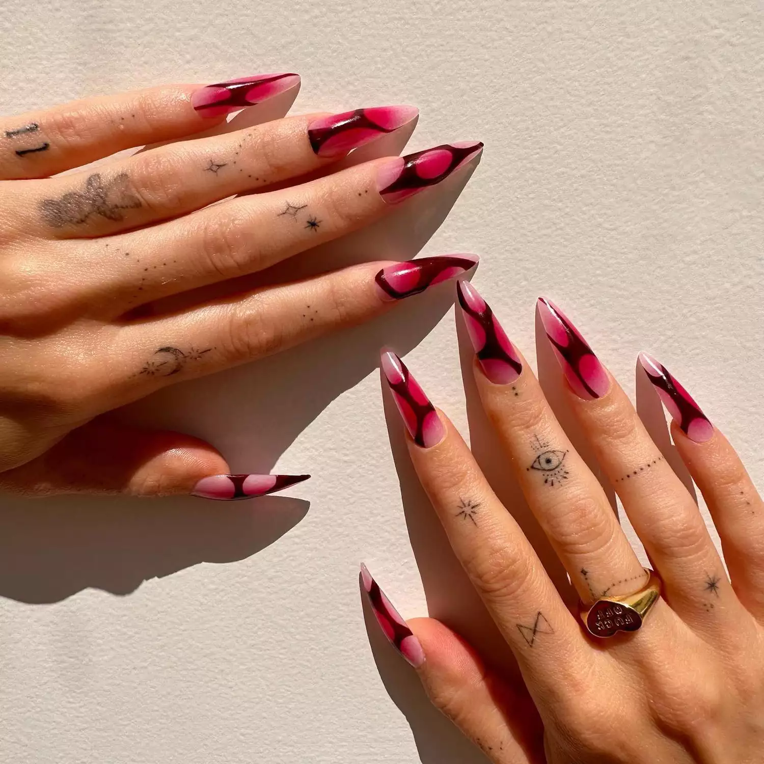 Bold pink ombrÃ© nails with black abstract designs