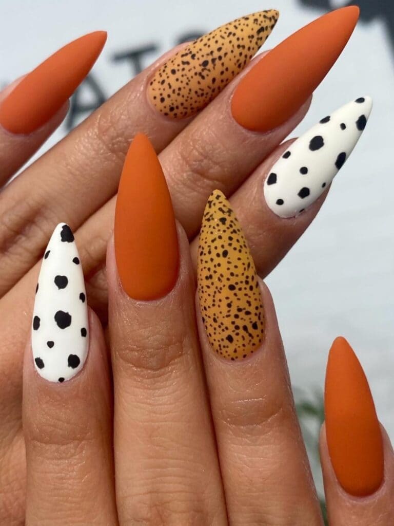 Matte burnt orange, Dalmatian, and sand nails in stilettos