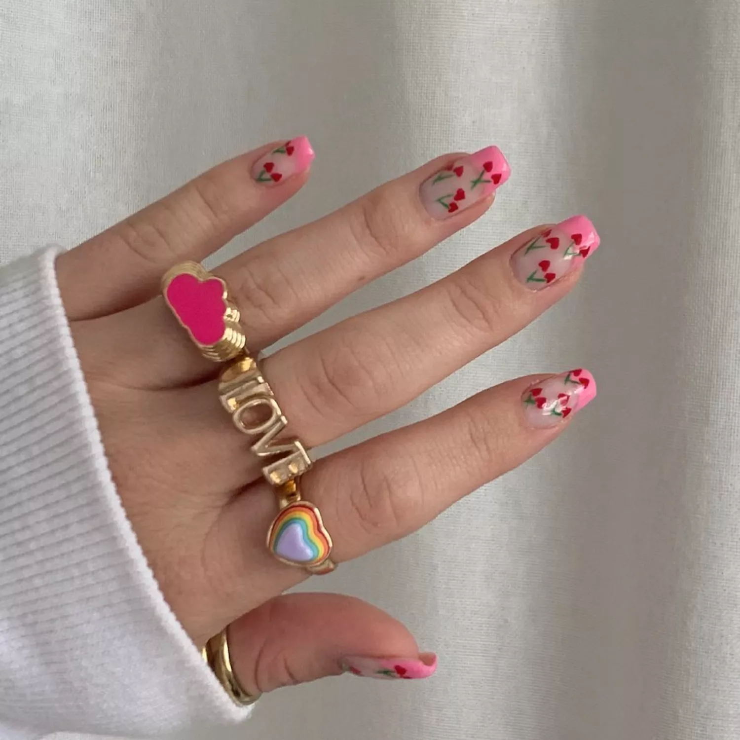 Neutral nails with pink French tips and heart-shaped cherry nail design