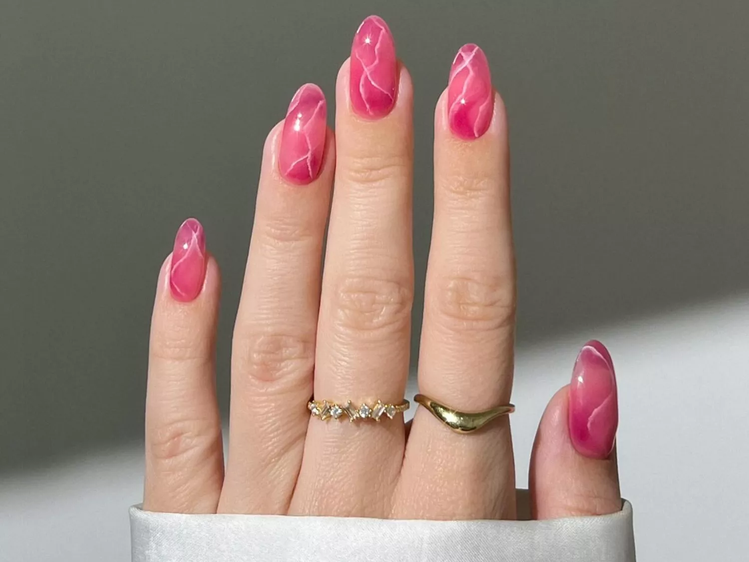 A pink manicure with lines on it that resemble a rose quartz crystal design