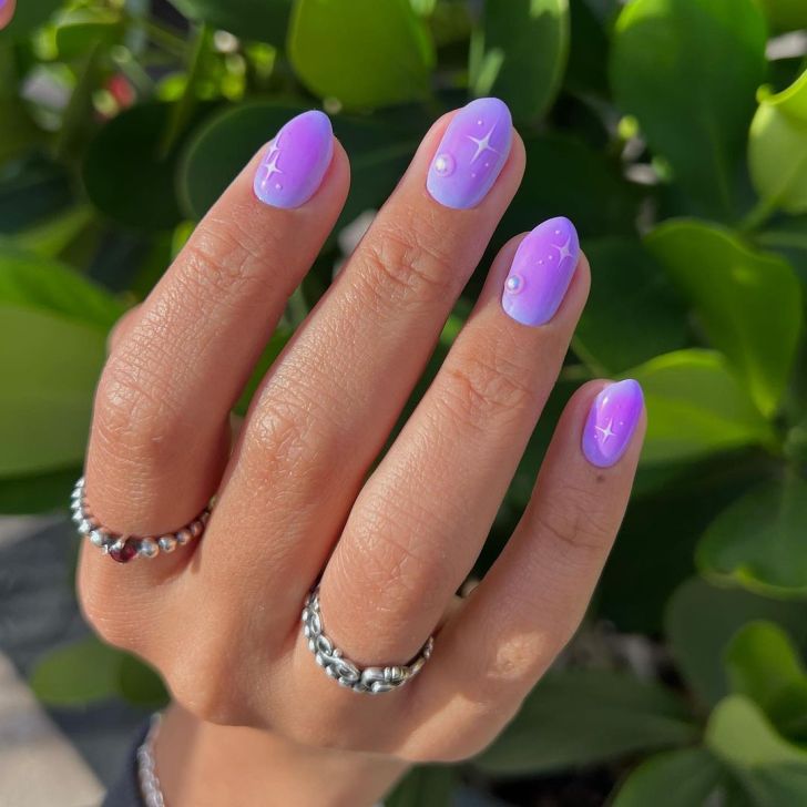 short purple aura nails with a white star design and pearl details