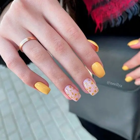 Square nails with a bright yellow base and pink accent nails featuring gold glitter details. This cheerful and sparkling design is perfect for adding a touch of glamour to your summer style.