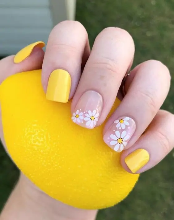 Bright yellow square nails featuring simple white and yellow daisy designs on accent nails. This charming and cheerful look captures the essence of a sunny summer day, perfect for any summer event.