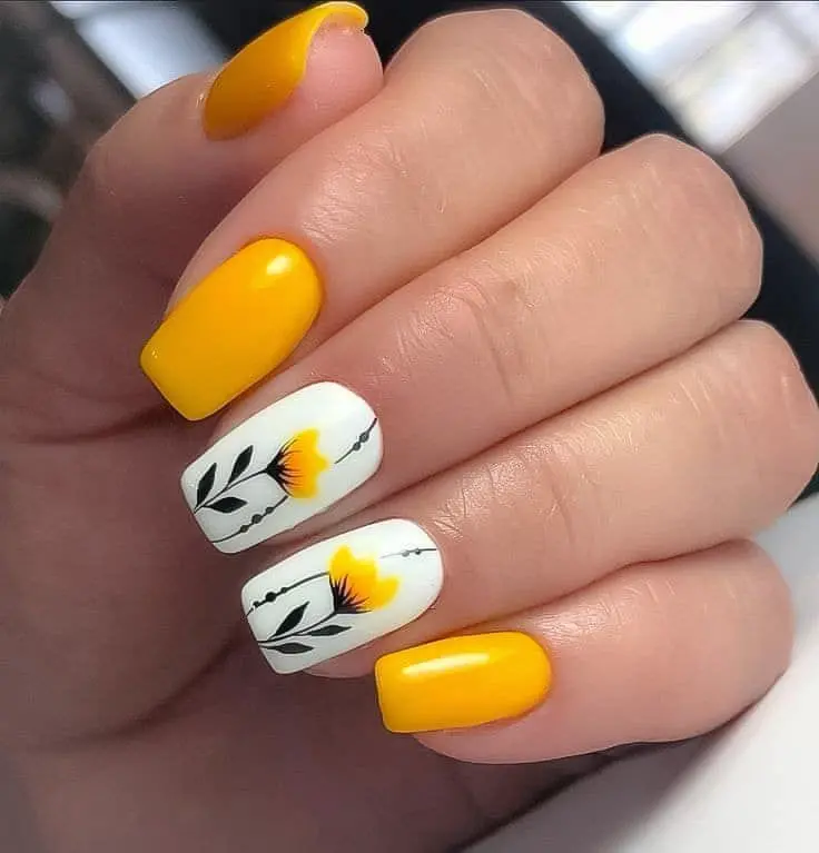 Featuring a mix of solid yellow nails and white nails with black and yellow floral designs, these square nails offer a stylish and sophisticated summer look, blending nature and brightness.