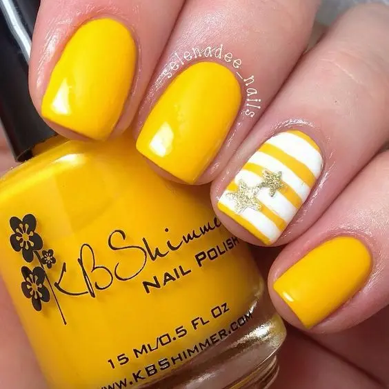 Vibrant yellow square nails paired with a white accent nail featuring yellow stripes and golden stars. This bold and playful design captures the essence of a sunny summer day.