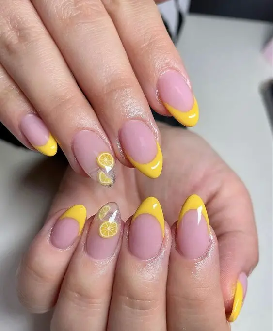 Stiletto nails featuring yellow French tips and detailed lemon slice designs on accent nails. This playful and refreshing design is perfect for a summer day.