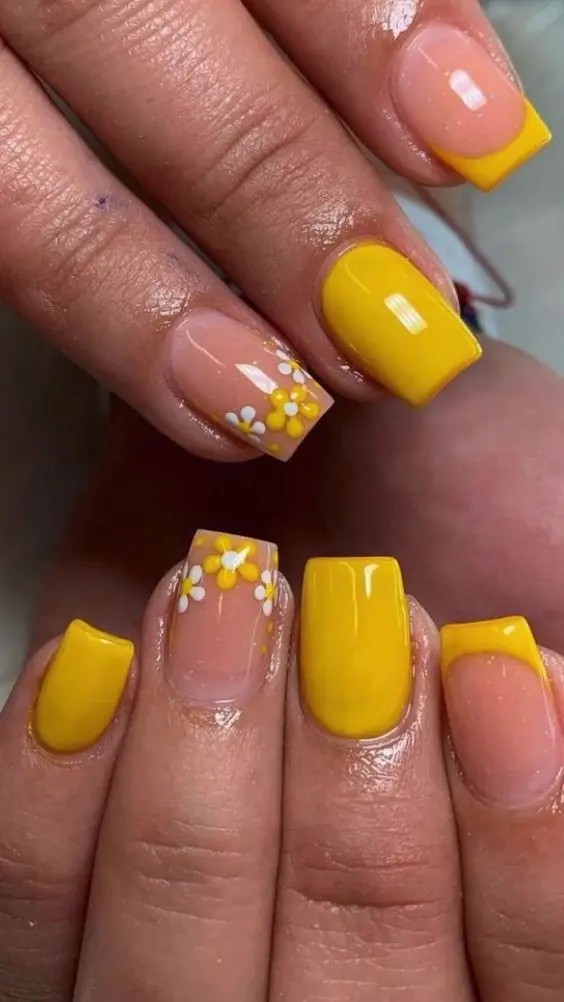 Square nails featuring bright yellow French tips, complemented by accent nails adorned with white and yellow daisies. Perfect for a vibrant summer look, exuding freshness and joy.