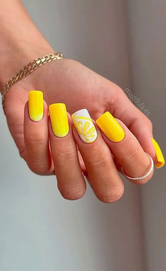 Square nails in a gradient of yellow to white create a striking ombre effect. The accent nail has a detailed lemon slice design, making this look vibrant and ideal for a fresh summer statement.