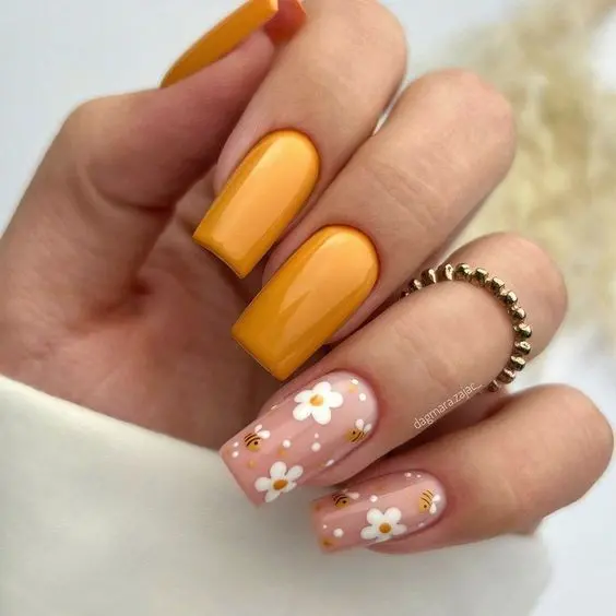 Glossy yellow square nails paired with pink accent nails decorated with white daisies and tiny bees. This playful and vibrant style is perfect for embracing the lively summer spirit.