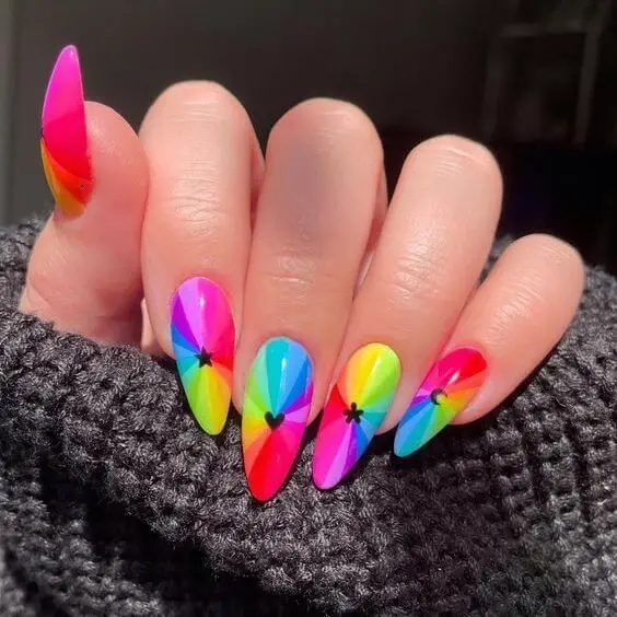 These pointed almond nails boast an innovative design with overlapping neon colors forming a starburst pattern. Each nail is a canvas of red, yellow, green, blue, and pink, ideal for making a dramatic fashion statement.