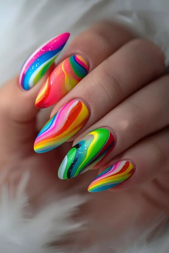 Stunning long almond nails featuring a neon rainbow swirl design. These nails combine vibrant shades of pink, yellow, green, blue, and orange, flowing into each other with a glossy finish. Perfect for a bold, cheerful statement.