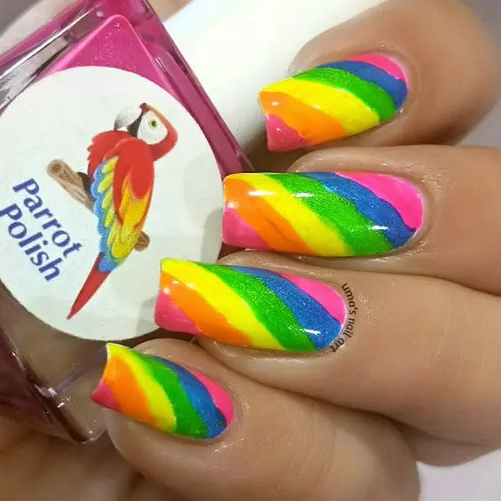 The neon rainbow nail design showcases vibrant diagonal stripes in pink, orange, yellow, green, blue, and purple, creating a bold and cheerful look. The nails are square-shaped, adding a modern touch. This lively style is perfect for expressing a fun and colorful personality, making a statement with every gesture.