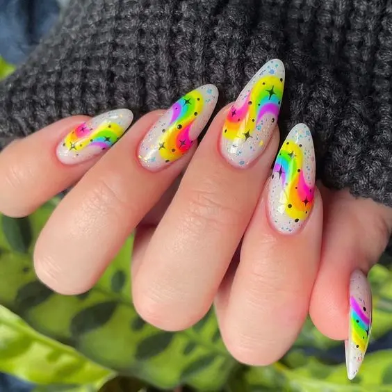 Unique and artistic, these long almond nails feature splattered neon paint in rainbow colors on a clear glitter base. This design is perfect for anyone looking to make a bold statement with a fun, party-ready look.