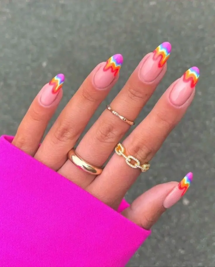 Chic almond-shaped nails with neon rainbow zigzag patterns over a natural base. This design offers a playful yet sophisticated look, ideal for those who wish to combine a subtle nail base with a burst of color.