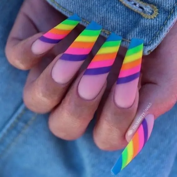 Long ballerina nails with a stunning array of neon rainbow stripes across a natural base. The sharp, clean lines of the stripes present a modern look that is both eye-catching and vibrant, perfect for a playful and energetic aesthetic.