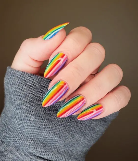 Long, stiletto-shaped nails display a sleek and sophisticated rainbow gradient with vertical stripes in neon colors. The design’s clean lines and vibrant palette make it an eye-catching and elegant choice, suitable for making a bold fashion statement.