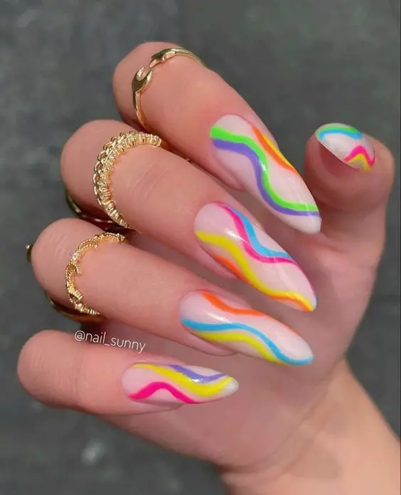 Soft almond-shaped nails elegantly painted with wavy neon rainbow stripes over a translucent base. This whimsical design offers a playful yet subtle nod to the vibrant colors of the rainbow, perfect for a fresh, youthful look.