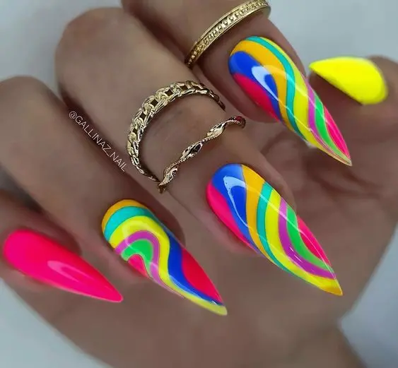 These nails feature a bold neon rainbow design with swirling patterns in vibrant colors on stiletto-shaped nails. The intricate swirls and bright hues give a lively and energetic vibe, perfect for adding a pop of color and fun to any look.