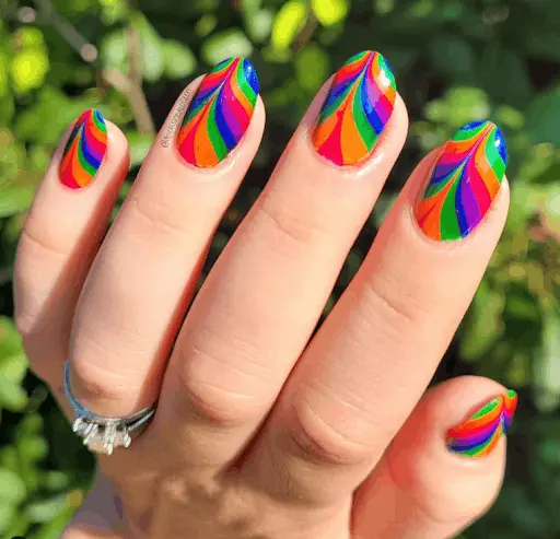 Long rounded nails with intricate swirling rainbow patterns that mimic the art of painting. Each nail features bold, interlocking colors that provide a stunning visual flow, suitable for creative personalities and artsy events.