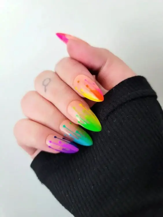 These nails feature a neon rainbow gradient with dripping paint effects on stiletto-shaped nails. The vibrant blend of colors, transitioning from pink to green, creates a playful and artistic style. Perfect for someone looking to showcase their creative and fun personality.