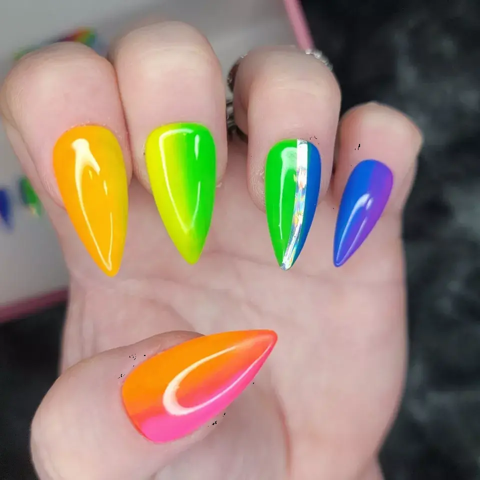 These stiletto-shaped nails feature a neon rainbow gradient with glossy transitions from yellow to purple. The vibrant colors create a bold, playful look, perfect for an energetic personality. A metallic stripe adds a modern twist.