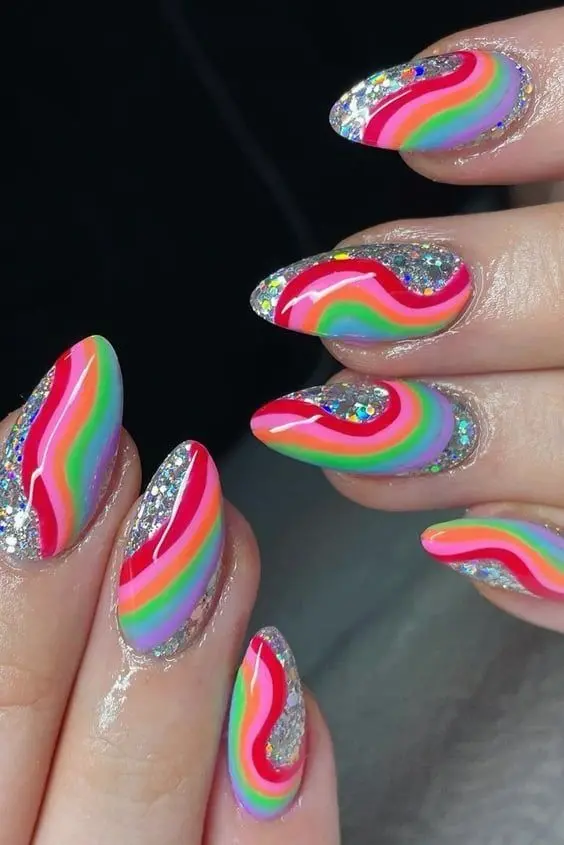 This nail design presents a whimsical twist on the neon rainbow theme with wavy, glitter-infused stripes of vivid colors on almond-shaped nails. The glitter accents add a touch of glamour, making these nails perfect for parties and festive occasions, highlighting a fun and festive personality.