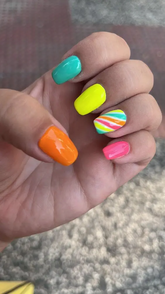 Squoval-shaped nails with a unique blend of neon colors. Each nail transitions from one color to the next, resembling the natural blending of a sunset, ideal for adding a pop of color to any fashion ensemble.