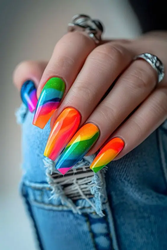 Stunning ballerina nails featuring a sharp gradient of neon rainbow colors, blending smoothly from one to another. The glossy finish enhances the vividness, making these nails a perfect choice for those looking to stand out.