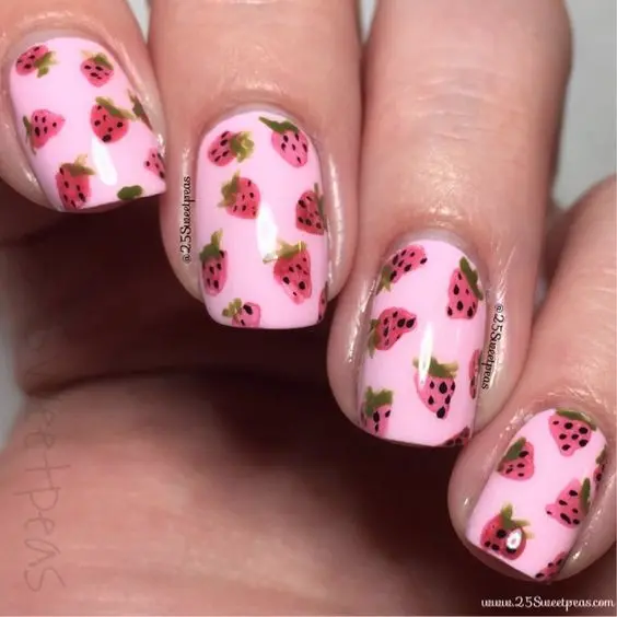 Soft pink nails serve as a canvas for scattered strawberry seeds and leaves, creating a subtle yet charming effect. This design is perfect for those who prefer a minimalist approach with a touch of playfulness.