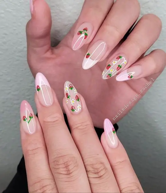 Elegant strawberry-themed nail art on stiletto-shaped nails, showcasing a soft pink base with delicate green and red strawberry patterns. This design combines sophistication with a touch of nature, suitable for casual and formal wear.