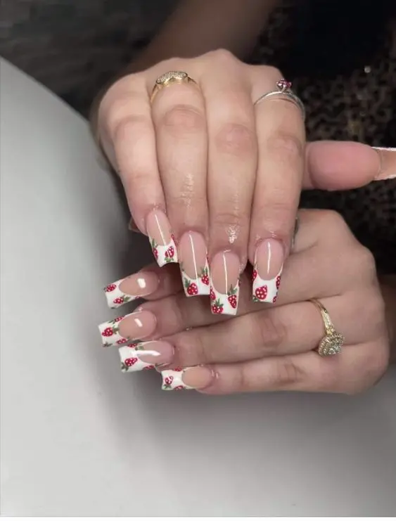 Long ballerina-shaped nails are elegantly styled with a French tip design interspersed with small strawberry patterns. The classic French manicure is enhanced with a fresh, fruity twist, suitable for both casual and formal occasions.