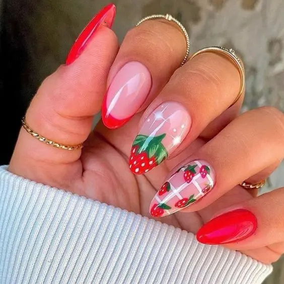 Vibrant red and soft pink gel nails with strawberry accents create a striking look. This playful style combines glossy red and matte finishes, accented with detailed strawberry and floral designs on transparent backgrounds, perfect for summer.