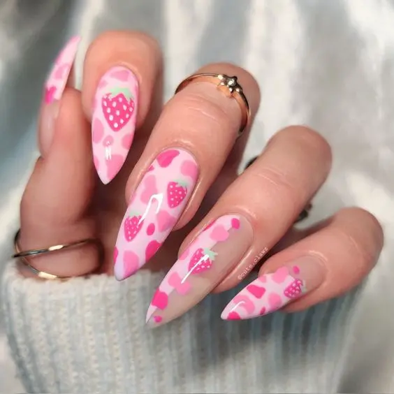 Charming stiletto-shaped nails with a vibrant pink base, adorned with strawberry and polka dot patterns in a symmetrical layout, offering a fun and youthful expression.