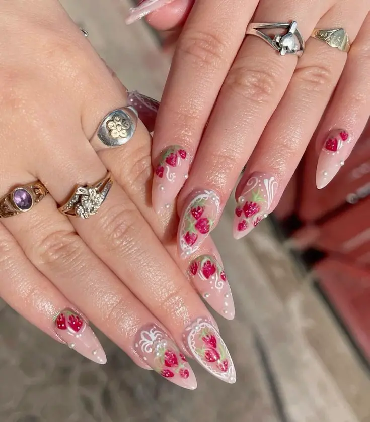 Elegant long stiletto nails featuring delicate strawberry patterns interspersed with floral designs, set against a translucent pink base, perfect for a sophisticated yet playful look.