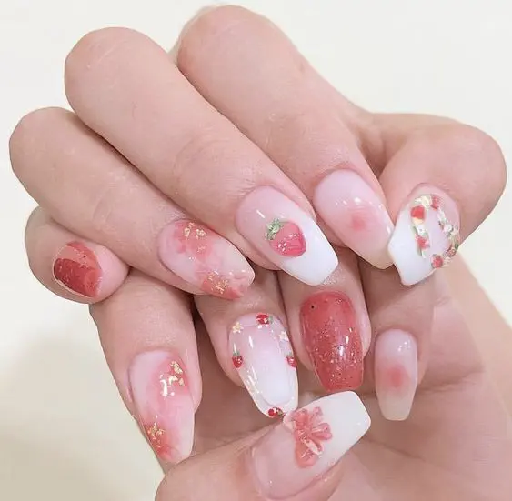 A delicate blend of soft pinks and white, these ballerina-shaped nails feature a faded effect with small strawberry designs and floral motifs. The subtle color palette and intricate details provide an elegant, feminine touch.