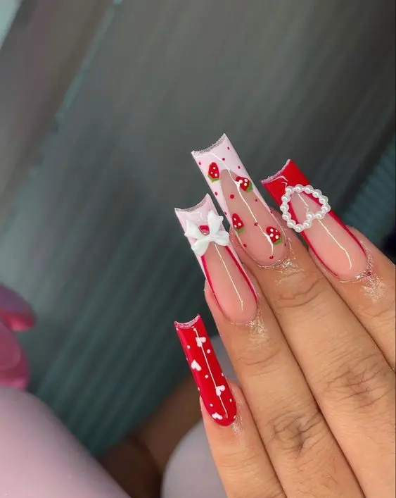 Long ballerina nails are dramatically accented with deep red and strawberry patterns, embellished with additional elements like bows and pearls. This design is perfect for those looking to make a bold statement with their nail art.