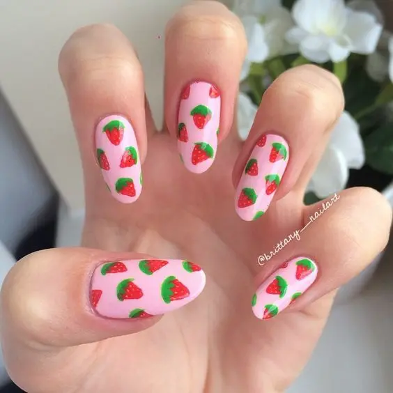 Bright strawberry designs pop against a soft pink background on these rounded nails, creating a vibrant and youthful look. The simple yet striking pattern is ideal for a casual, fun summer day.