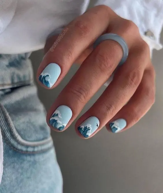 Short, squoval-shaped nails with a soft blue base and detailed ocean wave art. This simple yet elegant design captures the essence of the sea for a calm summer look.